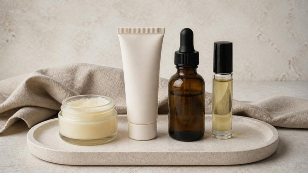 Pot de baume, tube de crème, flacon d'huile et roll-on alignés sur un plateau en pierre claire, article du Journal Calm&Co Image