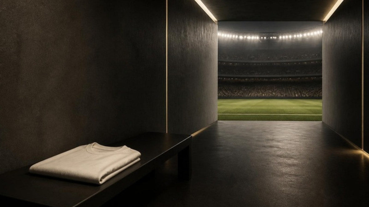 Couloir de vestiaire menant à la pelouse d'un stade éclairé, maillot plié sur un banc, article du Journal Calm&Co Image