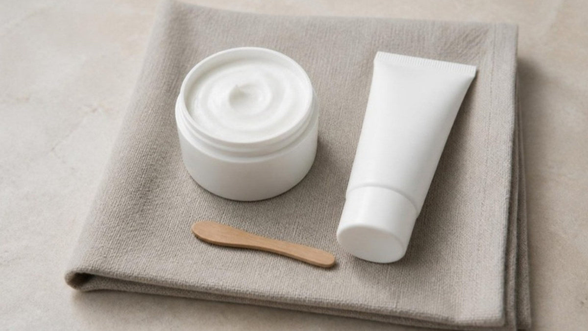 Pot de crème blanche ouvert et spatule en bois sur un linge de lin clair, article du Journal Calm&Co