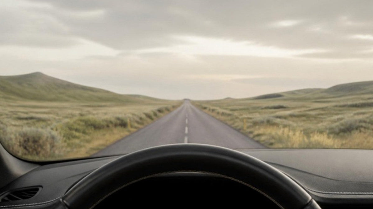 Route de campagne déserte vue depuis le poste de conduite d'une voiture à l'arrêt, article du Journal Calm&Co